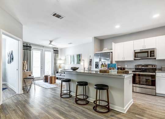 A kitchen with white cabinets and a wooden floor.