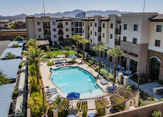 A large swimming pool surrounded by palm trees and apartment buildings.