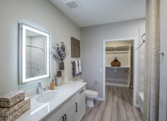 A bathroom with a white countertop and a large mirror.