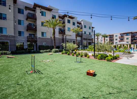 A grassy area in front of apartment buildings with a red object on the ground.