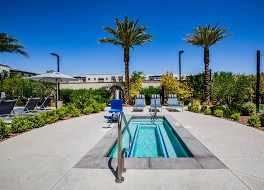 A pool surrounded by palm trees and lounge chairs.