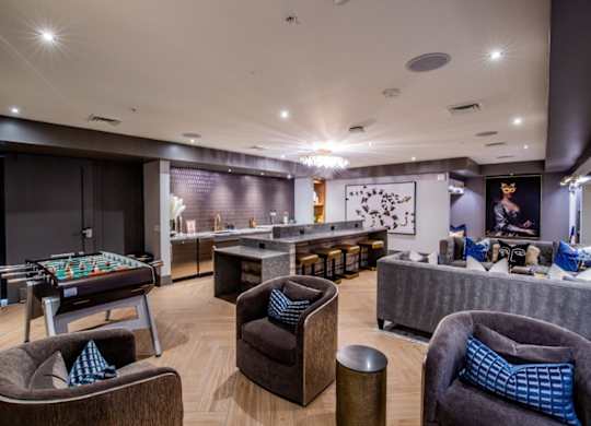 A room with a pool table and comfortable seating.