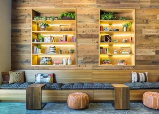 A room with a wooden wall and a couch with a cushion on it.