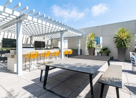 A patio with a table, chairs and a white pergola.