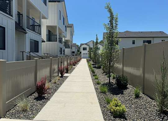 A long concrete walkway separates a row of white buildings.