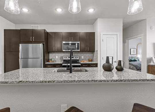 A kitchen with a granite countertop and dark brown cabinets.