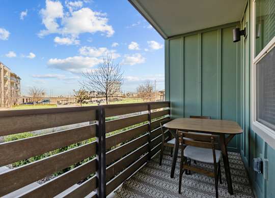 A small table and chair set up on a balcony.