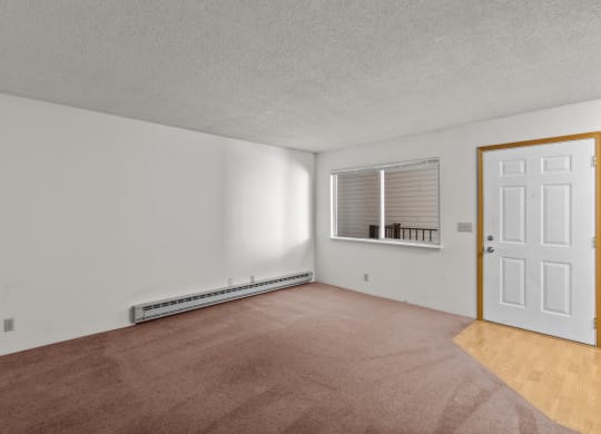 an empty living room with a white door and a window