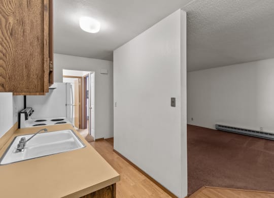 the kitchen and living room of an empty house with white walls and wood floors