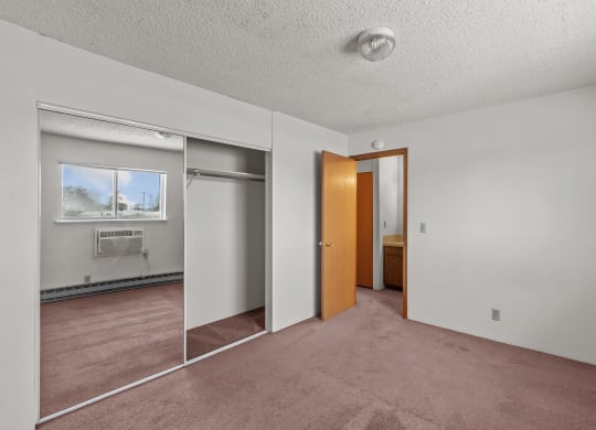 an empty room with a mirror and a door to a bathroom