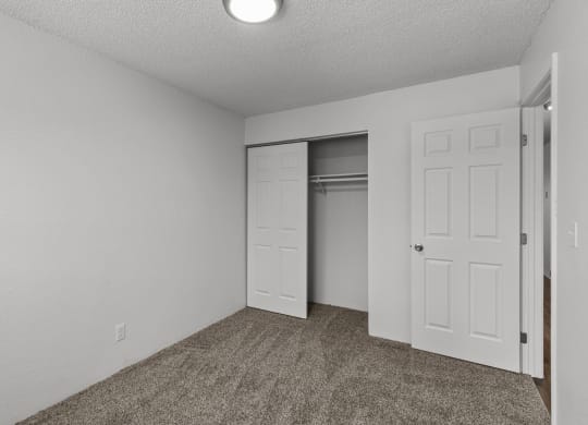 an empty bedroom with a closet and an open door