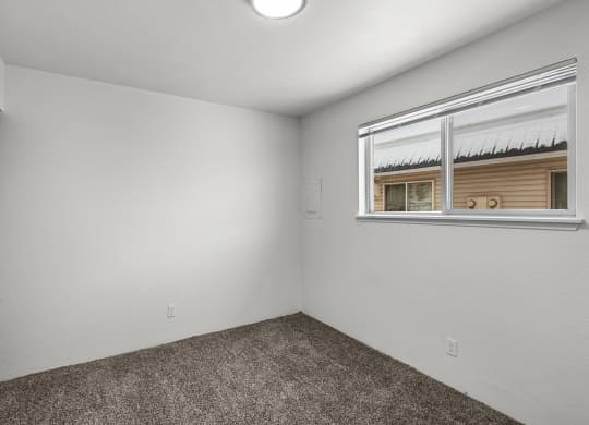 the living room of an empty home with a window and carpet
