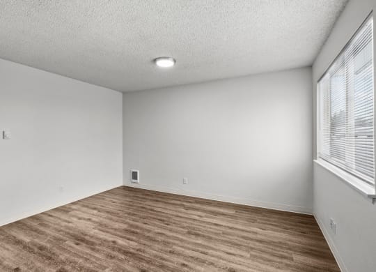 Creekside Apartments the spacious living room with a large window and wood flooring