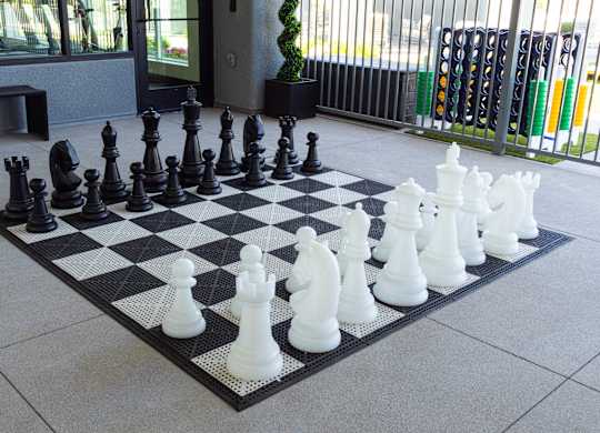 A giant chess set with black and white pieces on a black and white checkered board.