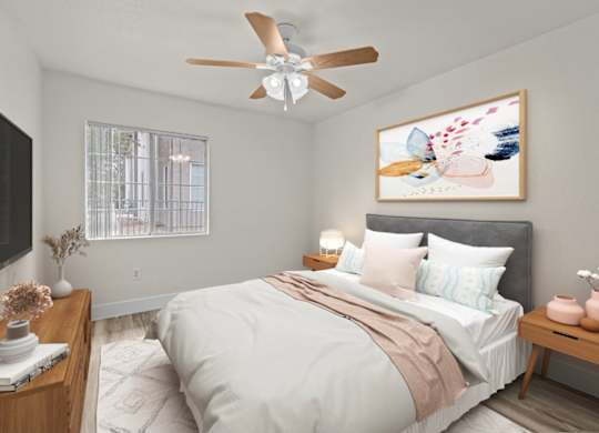 A bedroom with a bed, a ceiling fan, and a painting on the wall.