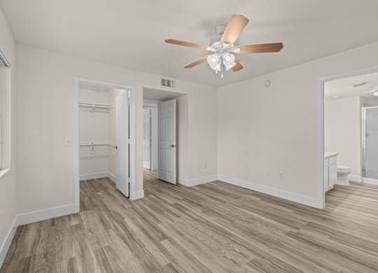 A room with a ceiling fan and wood flooring.