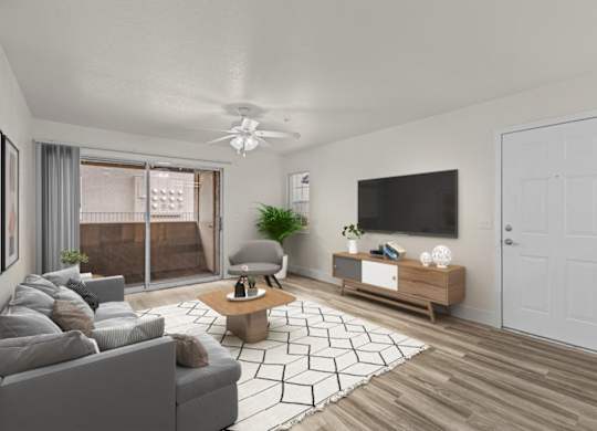 A living room with a grey couch, a coffee table, a flat screen TV, and a white door.