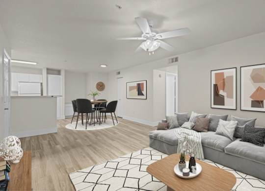 A living room with a grey couch, a coffee table, and a ceiling fan.