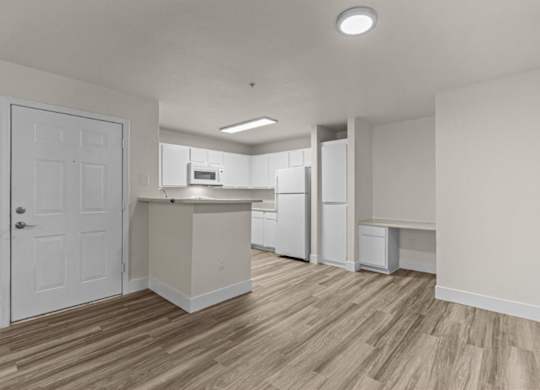 A kitchen with white appliances and a wooden floor.