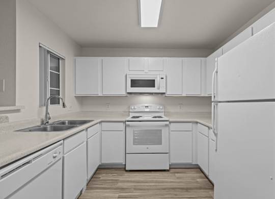 A white kitchen with a refrigerator, sink, and stove.