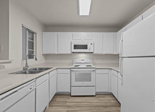 A white kitchen with a refrigerator, sink, and stove.