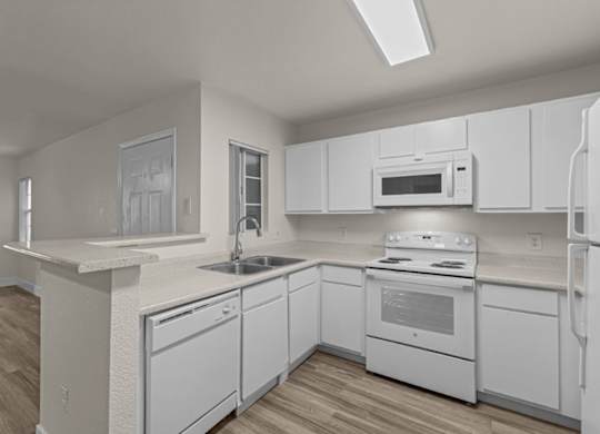 A white kitchen with wood flooring and white appliances.