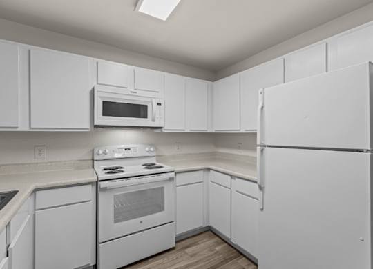 A white kitchen with a refrigerator, oven, and microwave.