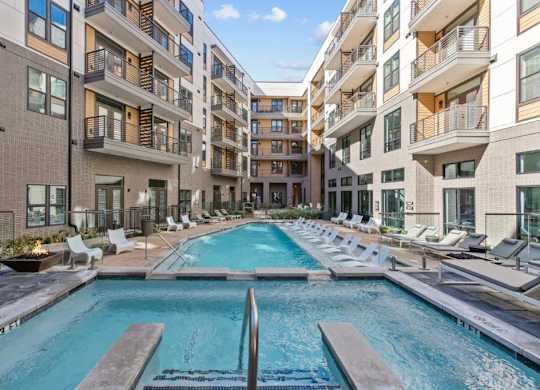 A swimming pool in the middle of a courtyard surrounded by apartment buildings.