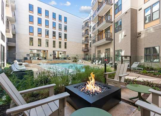 A fire pit sits in the middle of a patio surrounded by chairs and tables.