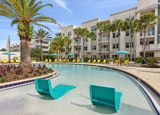 A pool with two green chairs in the foreground.