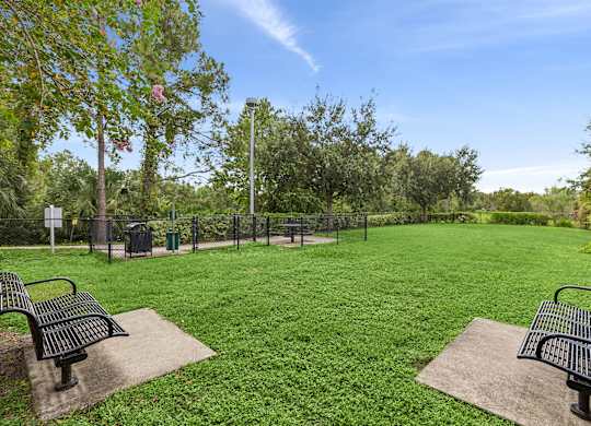 A park with two benches and a fence.