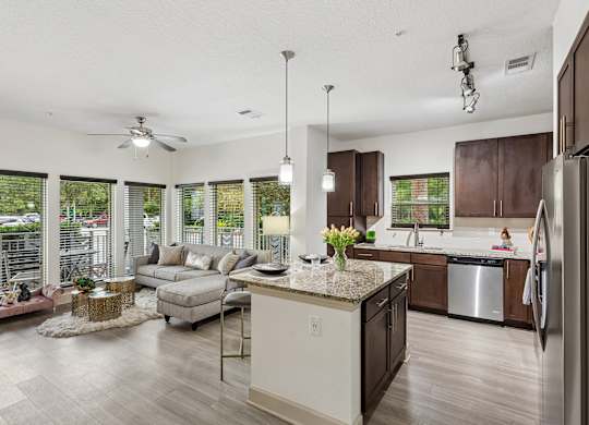 A modern kitchen with a large island and a living area with a couch and chairs.
