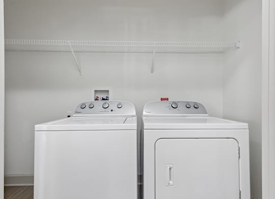 Two white front loading washing machines in a laundry room.