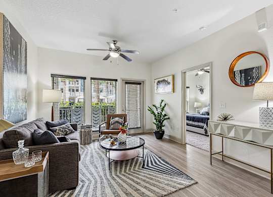 A living room with a striped rug and a round mirror on the wall.