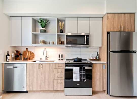 A modern kitchen with a refrigerator, microwave, and oven.