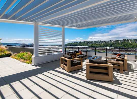A patio with a white roof and wooden furniture.