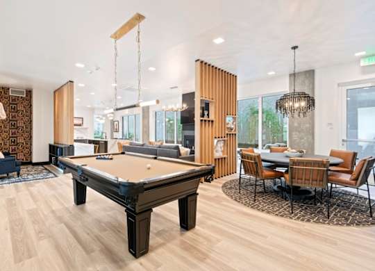 A pool table is in the middle of a room with a dining table and chairs.
