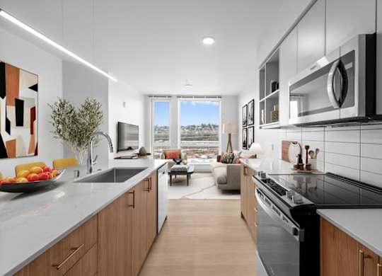 A modern kitchen with a view of the outdoors through a large window.