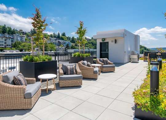 A patio with wicker chairs and tables overlooking a city.