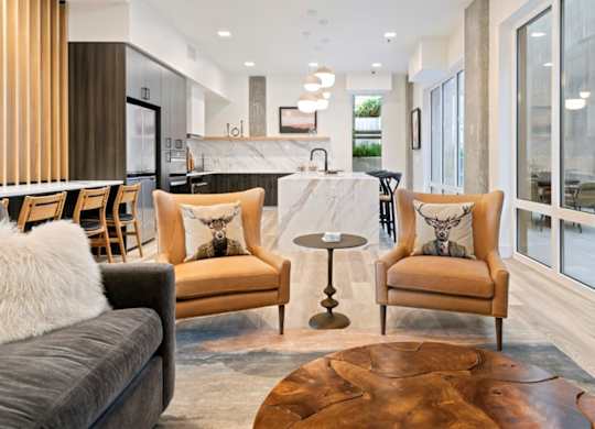 A modern living room with a grey couch, two chairs and a coffee table.
