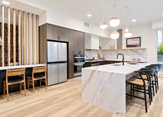 A modern kitchen with a marble island and wooden floors.