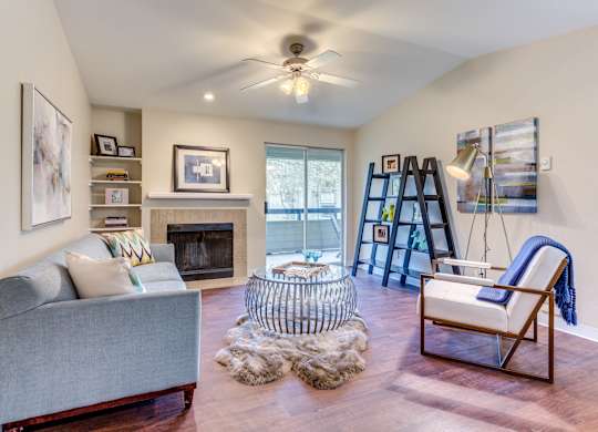 A living room with a grey couch, a fireplace, and a chair with a blue throw.