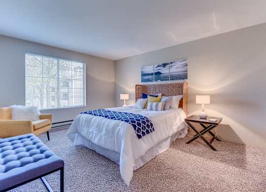 A bedroom with a large bed and a chair.