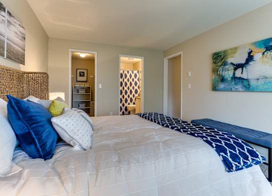 A bedroom with a large bed and a painting on the wall.