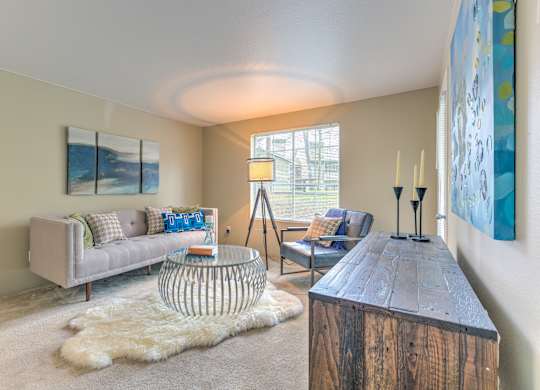 A living room with a grey couch, a wooden coffee table, and a white rug.