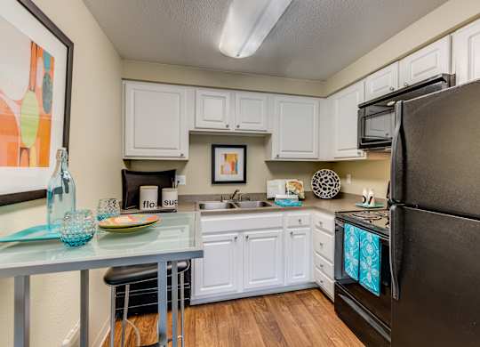A kitchen with white cabinets and a black refrigerator.