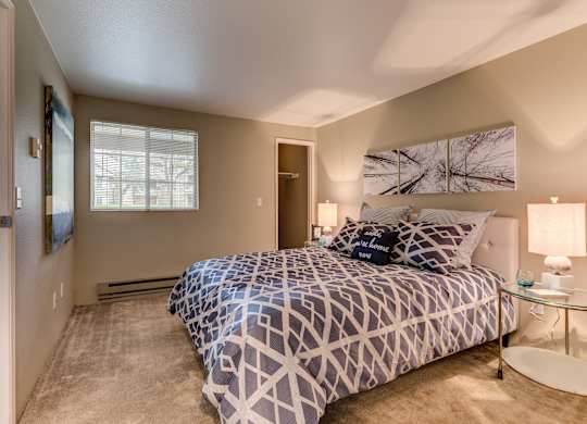 A bedroom with a bed, nightstand, and lamp.