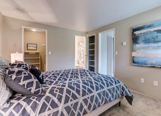 A bedroom with a large bed and a painting on the wall.