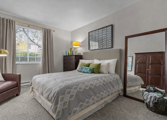 A bedroom with a large bed and a chair.