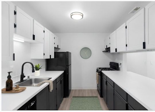 A kitchen with black cabinets and white countertops at The Rosewood Apartments in Vancouver, Washington.